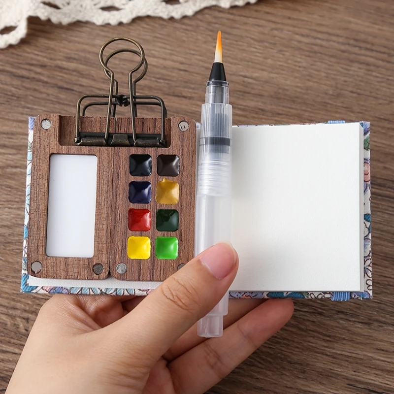Miniature wooden Schmincke watercolor set with palette, brush, and sketchbook