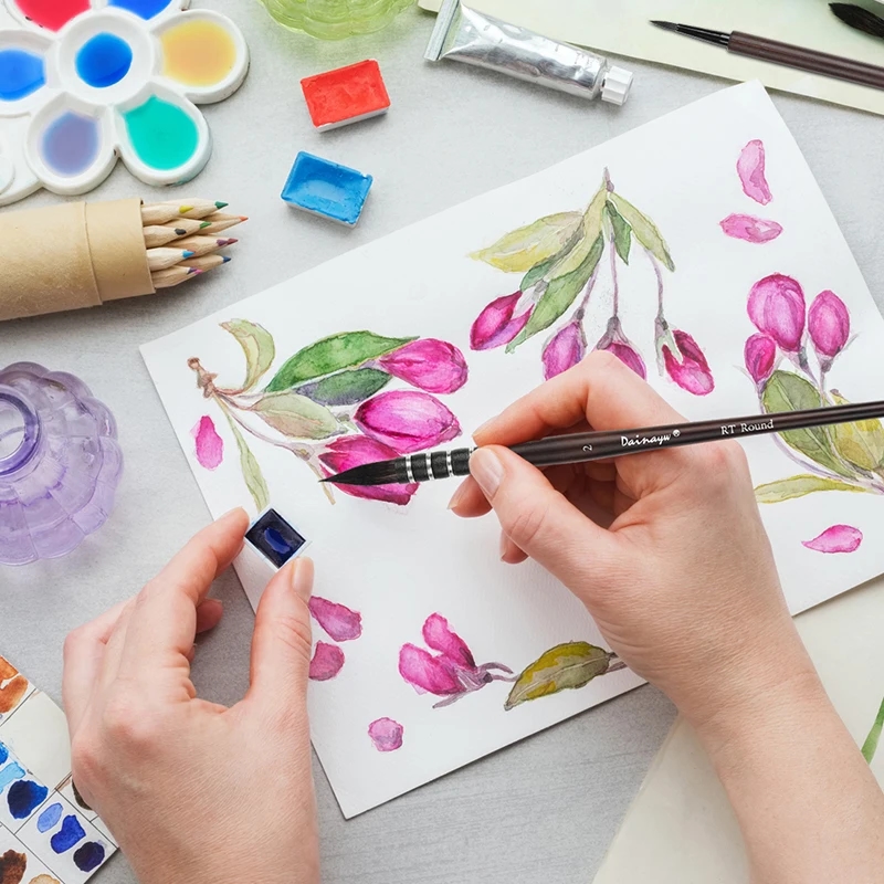 Watercolor brush set placed against a background of colorful watercolor paints