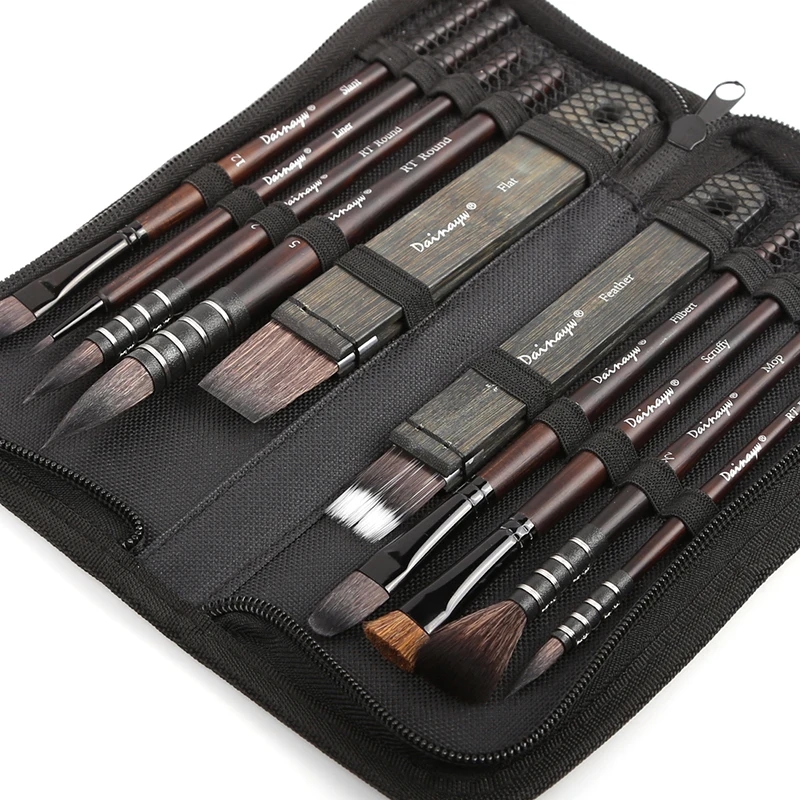 Artist holding watercolor brushes from the set to apply paint on paper