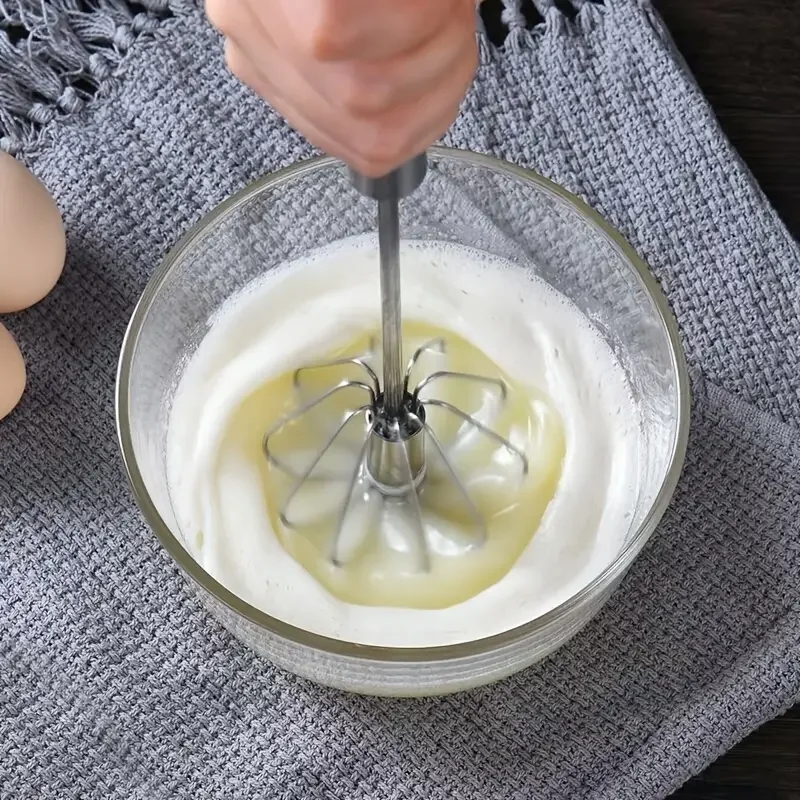 Whisk on a table with a cup and eggs