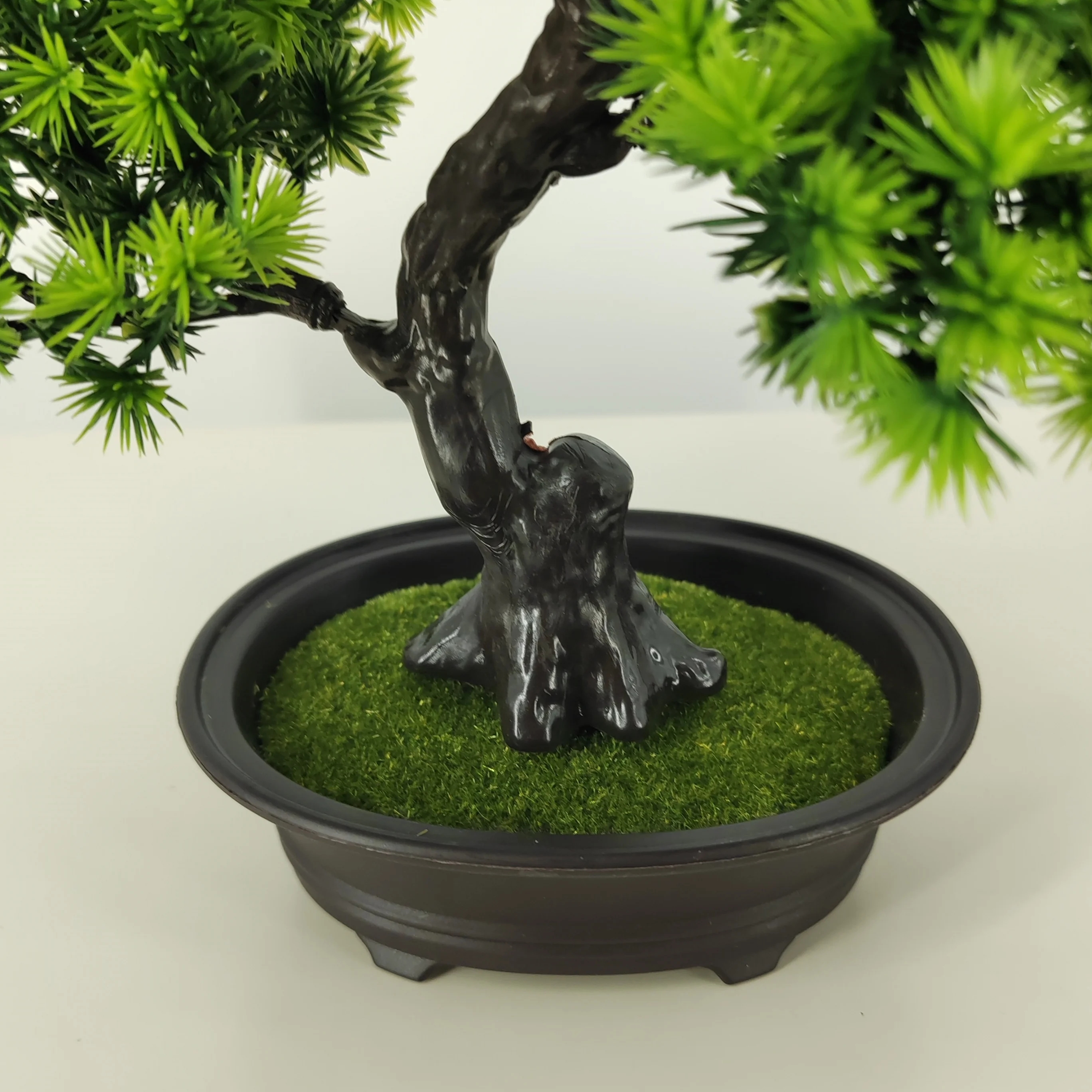 Árbol bonsái artificial elegante contra una pared blanca