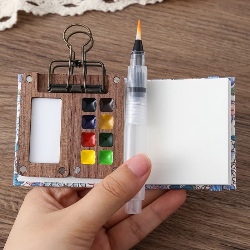 Miniature wooden Schmincke watercolor set with palette, brush, and sketchbook