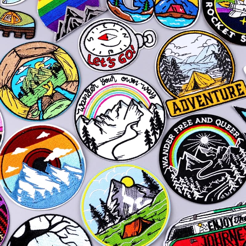 Embroidered patch with an image of a mountain landscape, a tent and a campfire for decorating clothing